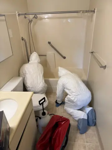 Experts Two experts with protective gear cleaning a restroom.